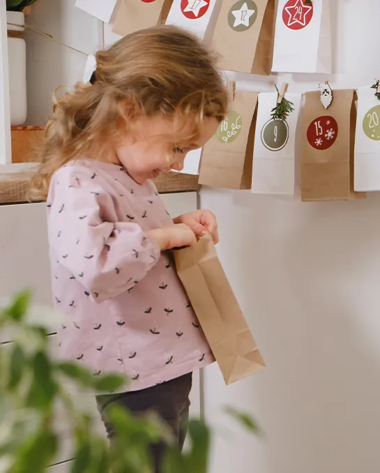 Das Mädchen öffnet die Papiertüte des Adventskalenders