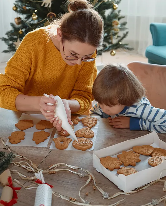 Eine Frau und ein Junge verzieren gemeinsam Weihnachtsplätzchen.