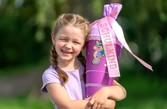 Mädchen hält lächelnd eine Schultüte im Arm