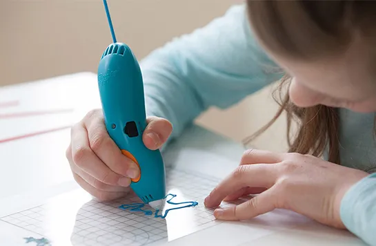Ein Kind zeichnet mit einem 3D-Stift auf einem Blatt Papier